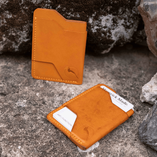 Two orange leather card holders on a stone surface with rocks in the background.
