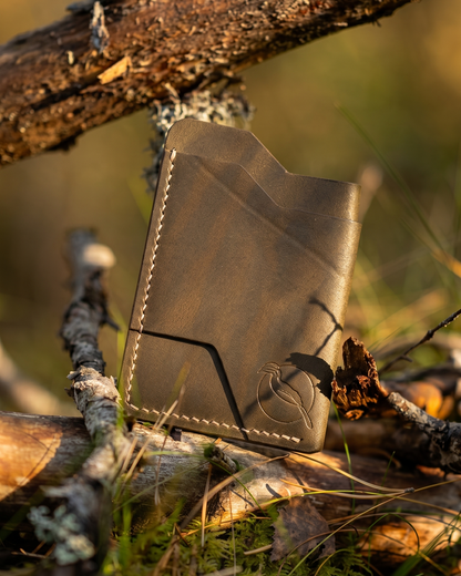 Handcrafted full grain leather cardholder wallet by Maverick Made. Singapore, photographed outdoors among forest branches and moss in warm golden hour light. Minimalist slim wallet made from premium vegetable tanned leather.